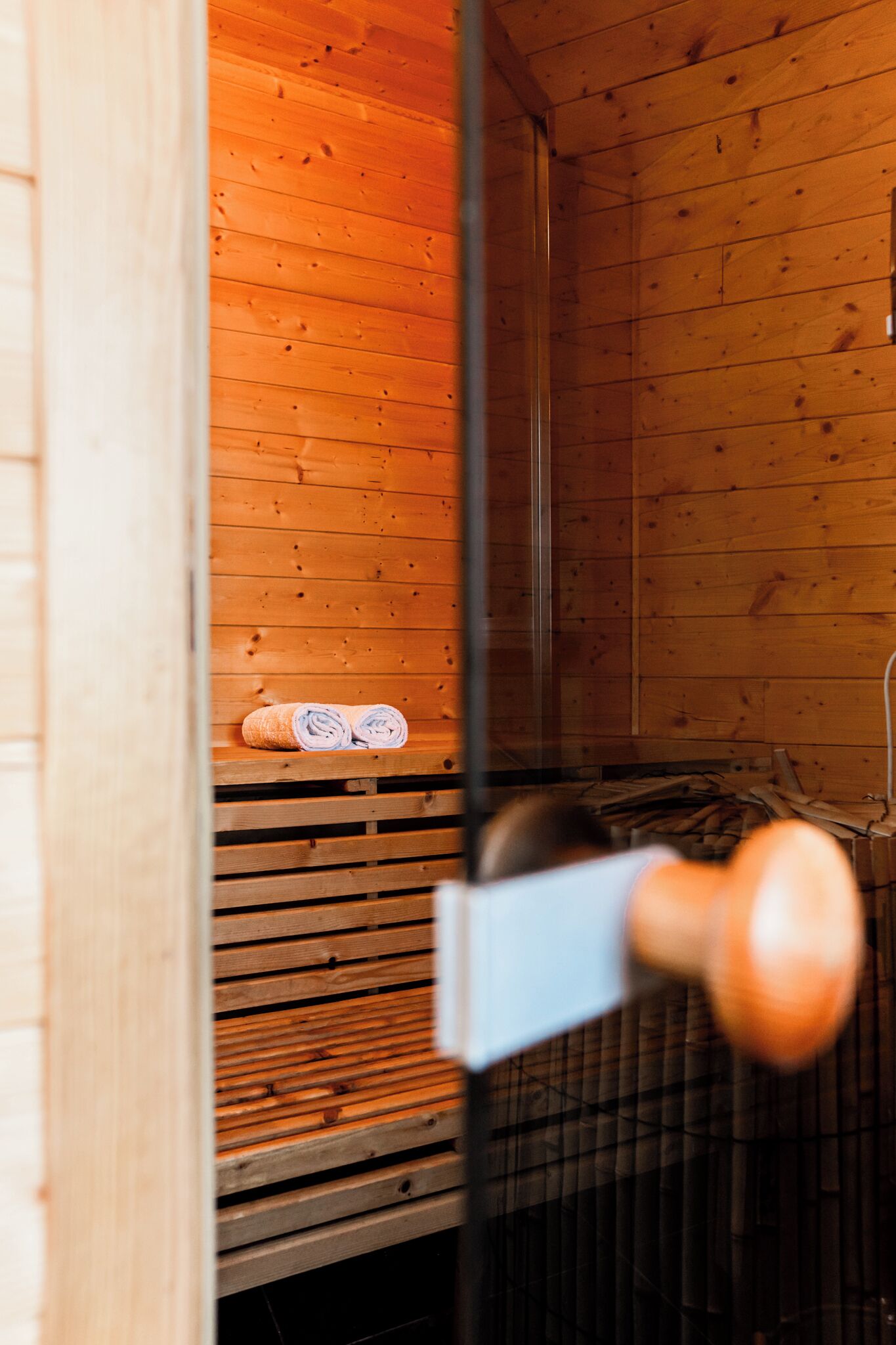 A wooden cabin interior with a bench and rolled towels.