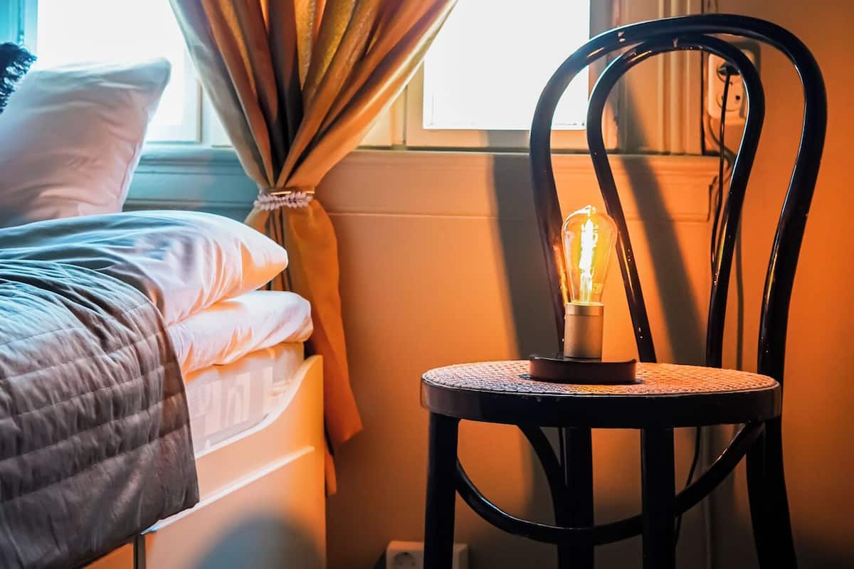 Una camera da letto con un letto, una sedia e una finestra con tende.
