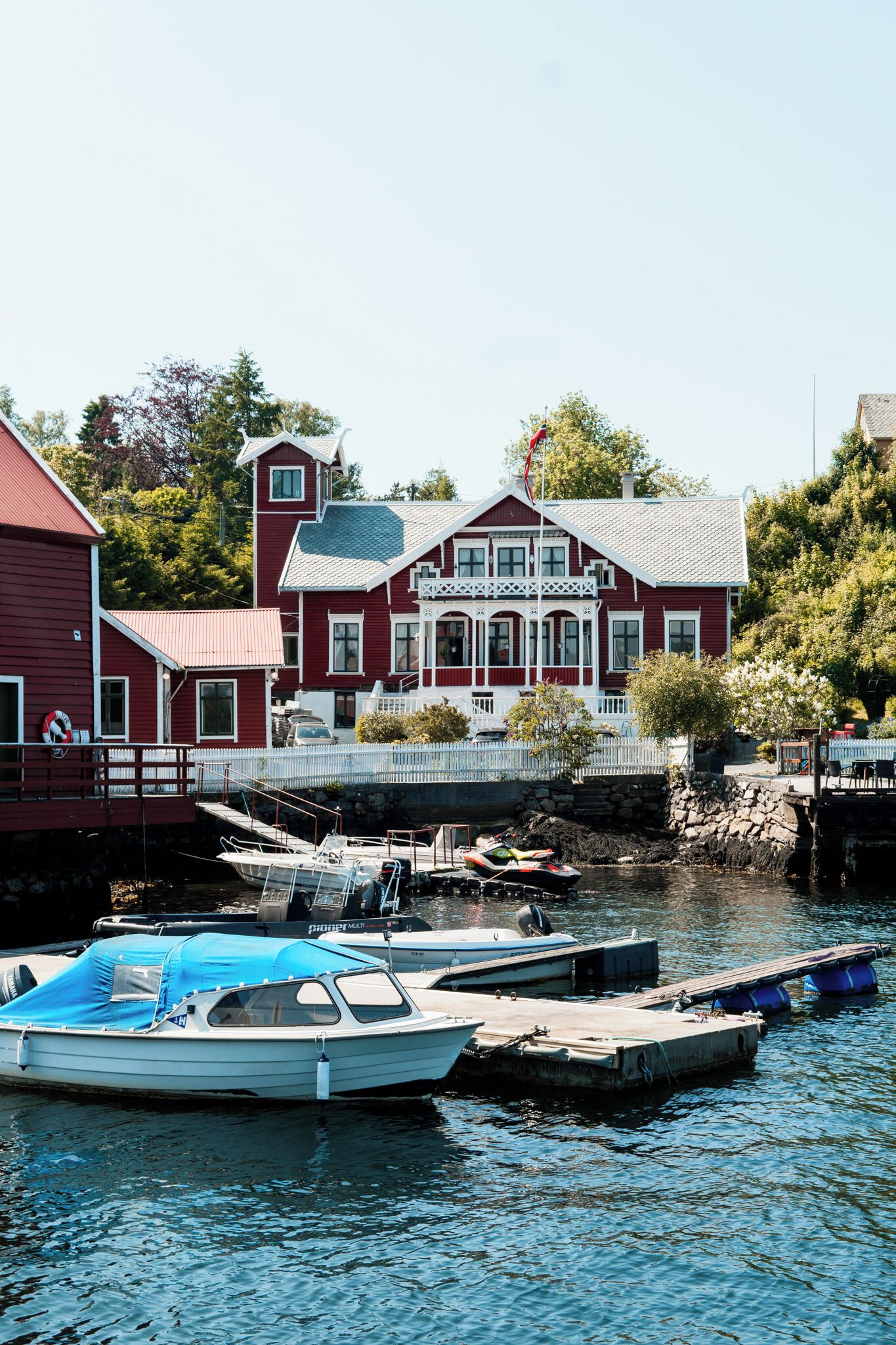 A red house with a dock and boats.