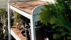 Un edificio rosso e bianco con veranda e giardino decorato con piante in vaso.