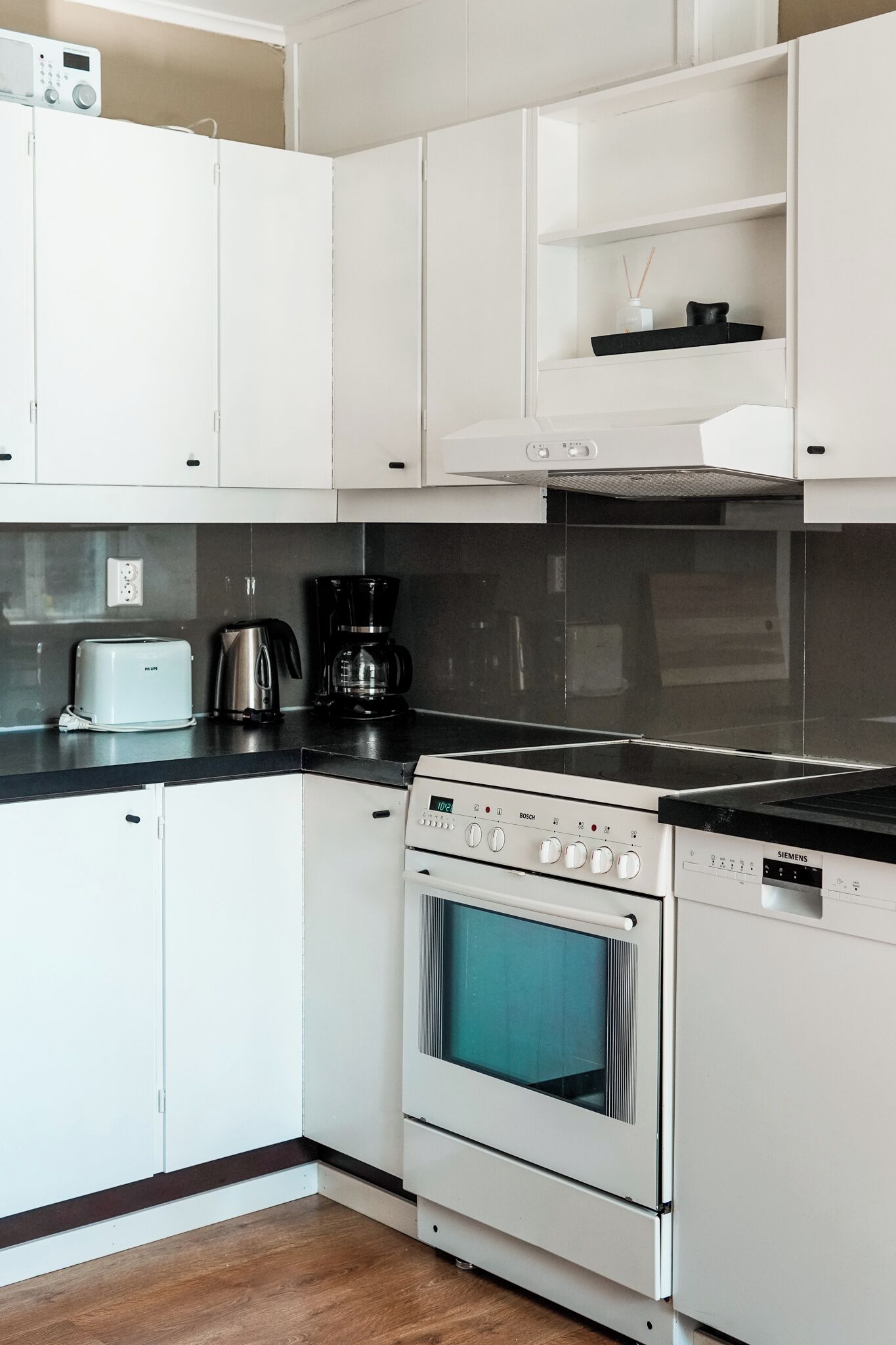 A modern kitchen with white cabinets, a Bosch oven, a Siemens microwave, and a coffee maker.