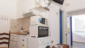 Eine kleine Küche mit Waschmaschine, Mikrowelle und einem Tisch mit Zeitschriften.