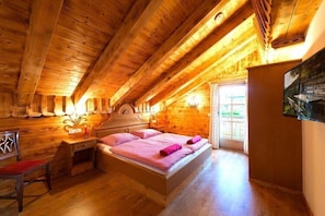 A wooden cabin bedroom with a bed, a desk, and a chair. - Chalet in St. Martin with Sauna & Mountain Views (St. Martin am Tennengebirge)