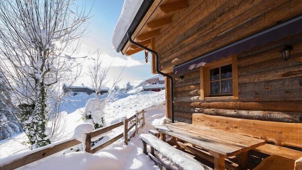 A wooden cabin with a wooden bench and table, surrounded by snow-covered ground and trees. - Chalet in St. Martin with Sauna & Mountain Views (St. Martin am Tennengebirge)