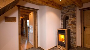 A cozy room with a stone fireplace, wooden beams, and a wooden door. - Chalet in St. Martin with Sauna & Mountain Views (St. Martin am Tennengebirge)