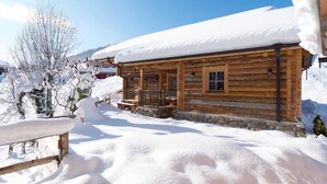A wooden cabin with a snow-covered roof and a stone foundation. - Chalet in St. Martin with Sauna & Mountain Views (St. Martin am Tennengebirge)