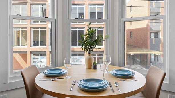 A dining table with blue plates, silverware, and a vase with green plants. - Steps Away From Mass Ave in Heart of Indy with Balcony (Indianapolis)