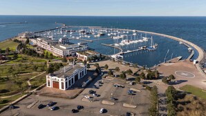 Luchtbeeld van een jachthaven met boten, een parkeerplaats en gebouwen.