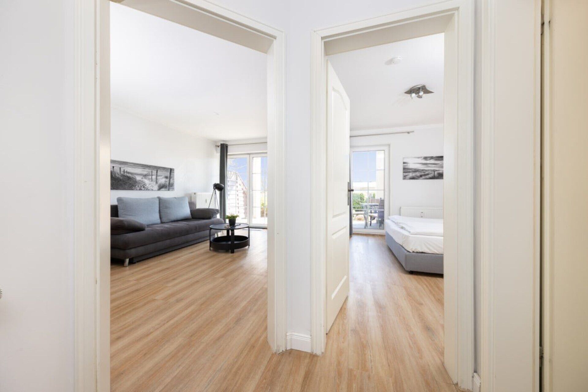 A modern apartment with a living area, a balcony, and a bedroom.