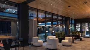 A modern lounge area with a wooden ceiling, large windows, and contemporary furniture. - NOTO Hotel (Reckange-sur-Mess)