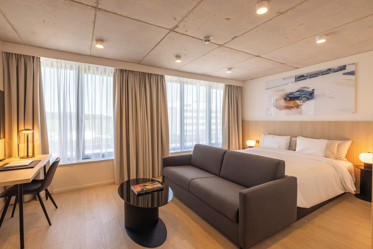 Una habitación de hotel moderna con una cama grande, un sofá, un escritorio y una mesa de centro.