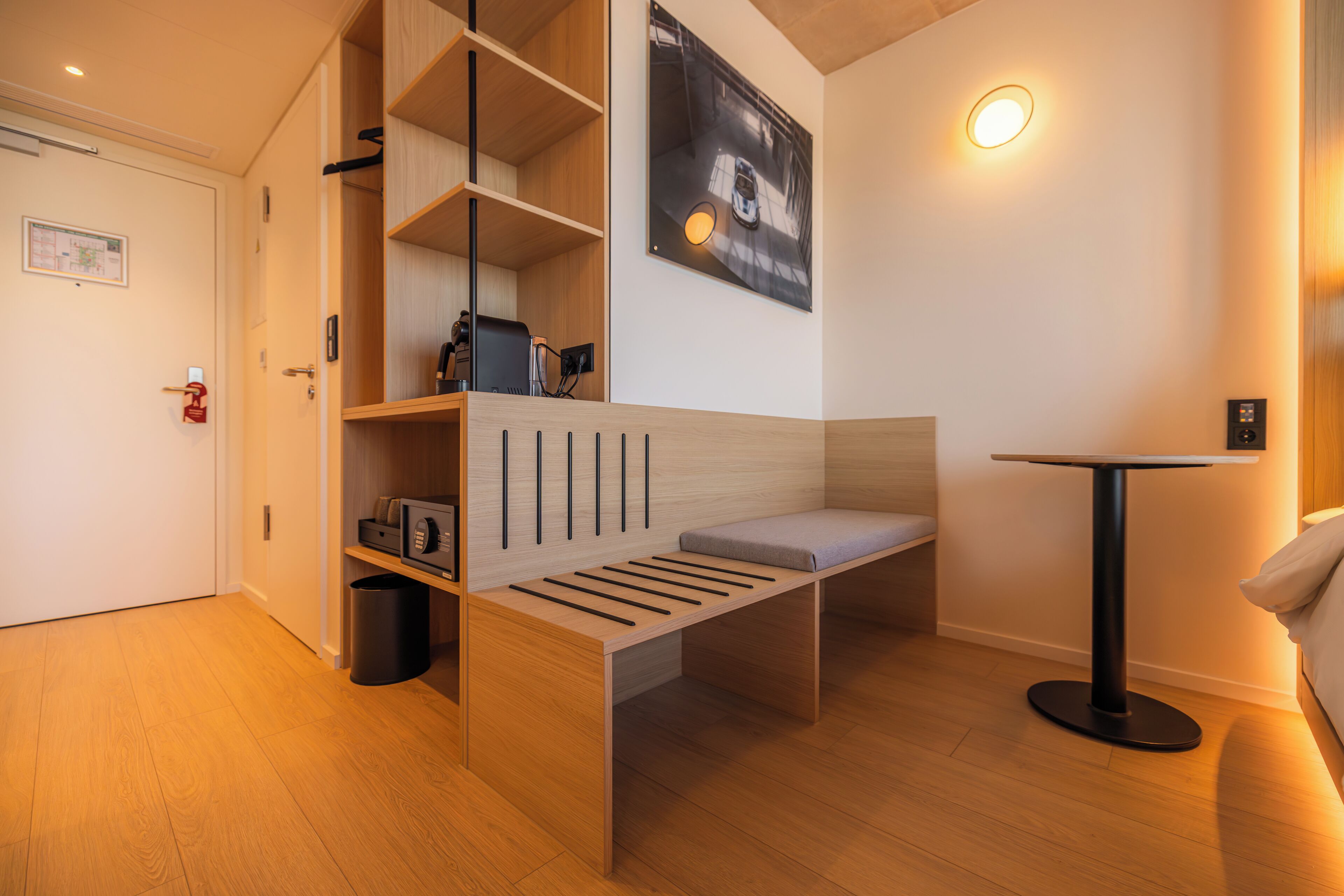 A modern room with a wooden bench, a small table, and a wall-mounted shelf with a picture.