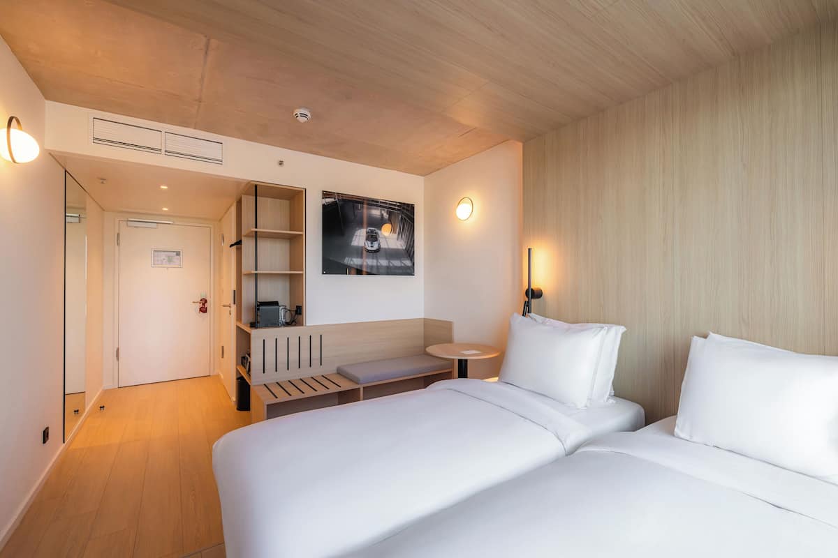 Una habitación de hotel moderna con una cama grande, un pequeño espacio de descanso, un televisor montado en la pared y una mesa redonda.