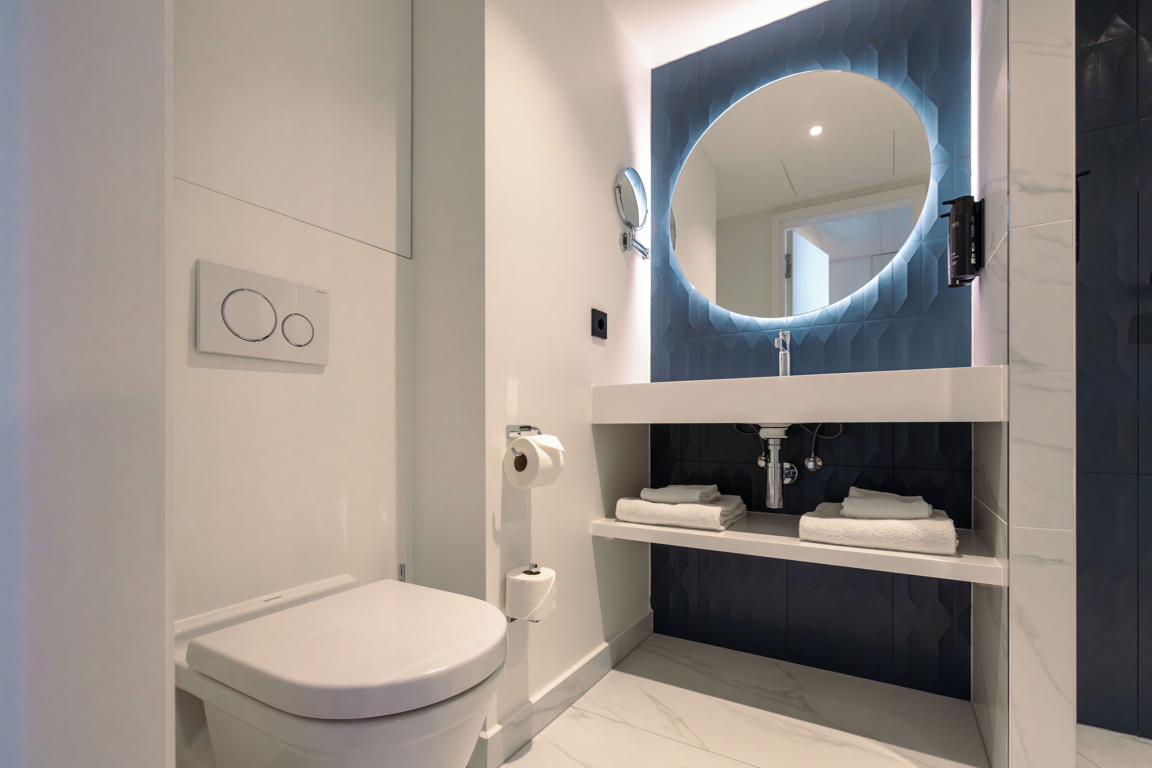 A modern bathroom with a toilet, a sink with a mirror, and a towel rack.