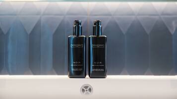Two black bottles labeled 'NOIR' on a white surface with a geometric patterned background.