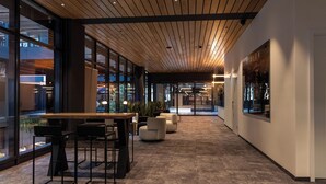 A modern interior with a long corridor, wooden ceiling, large windows, and seating areas. - NOTO Hotel (Reckange-sur-Mess)