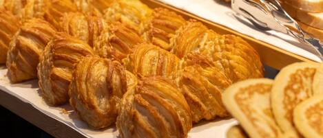 A display of pastries, including croissants and other baked goods, arranged on a wooden surface with a sign indicating 'Chavron Patisserie'.