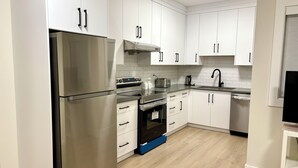 Una cocina moderna con armarios blancos, electrodomésticos de acero inoxidable y suelo de madera.