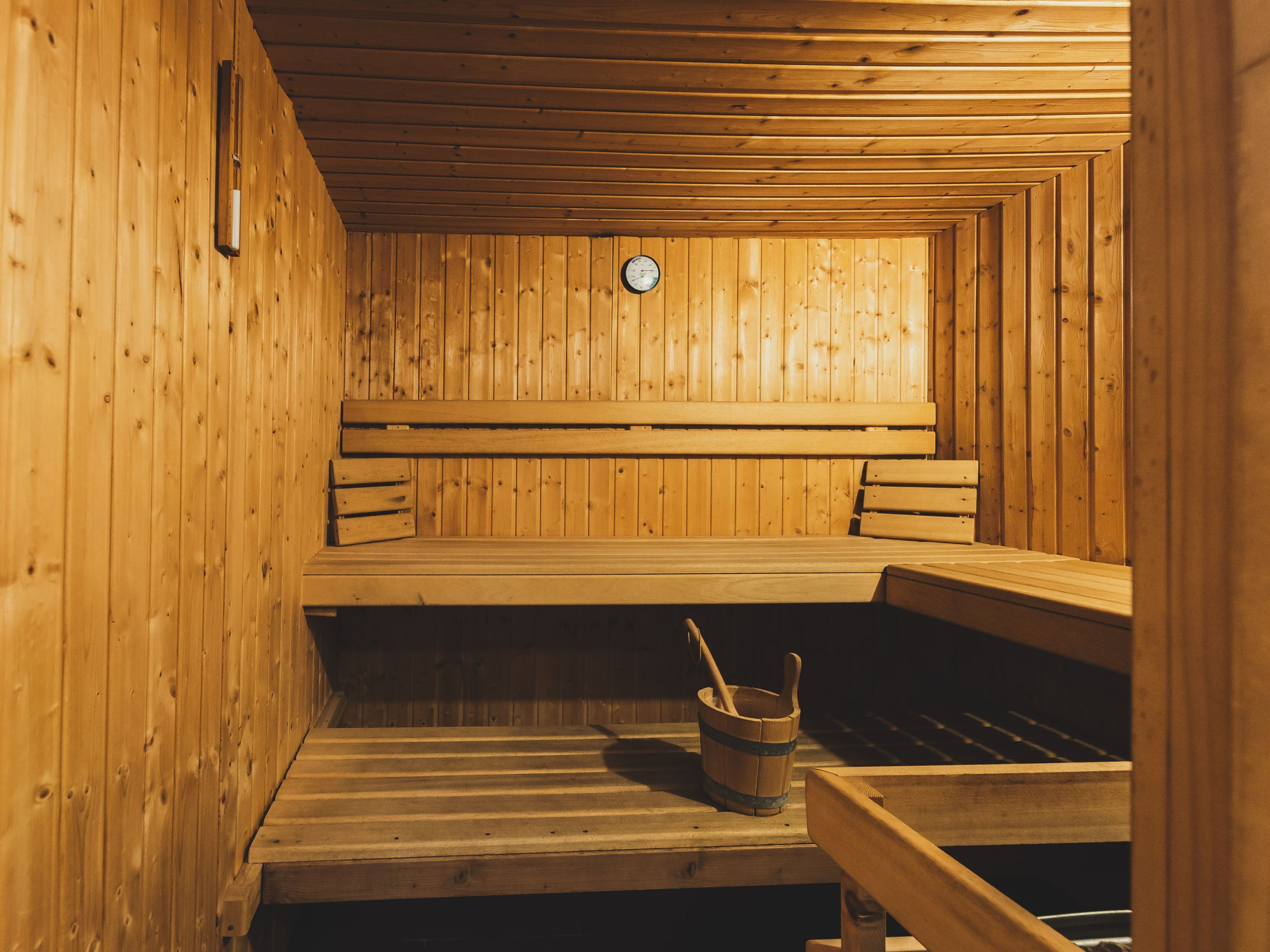 Uma sauna com bancos de madeira e um balde de madeira com uma concha.