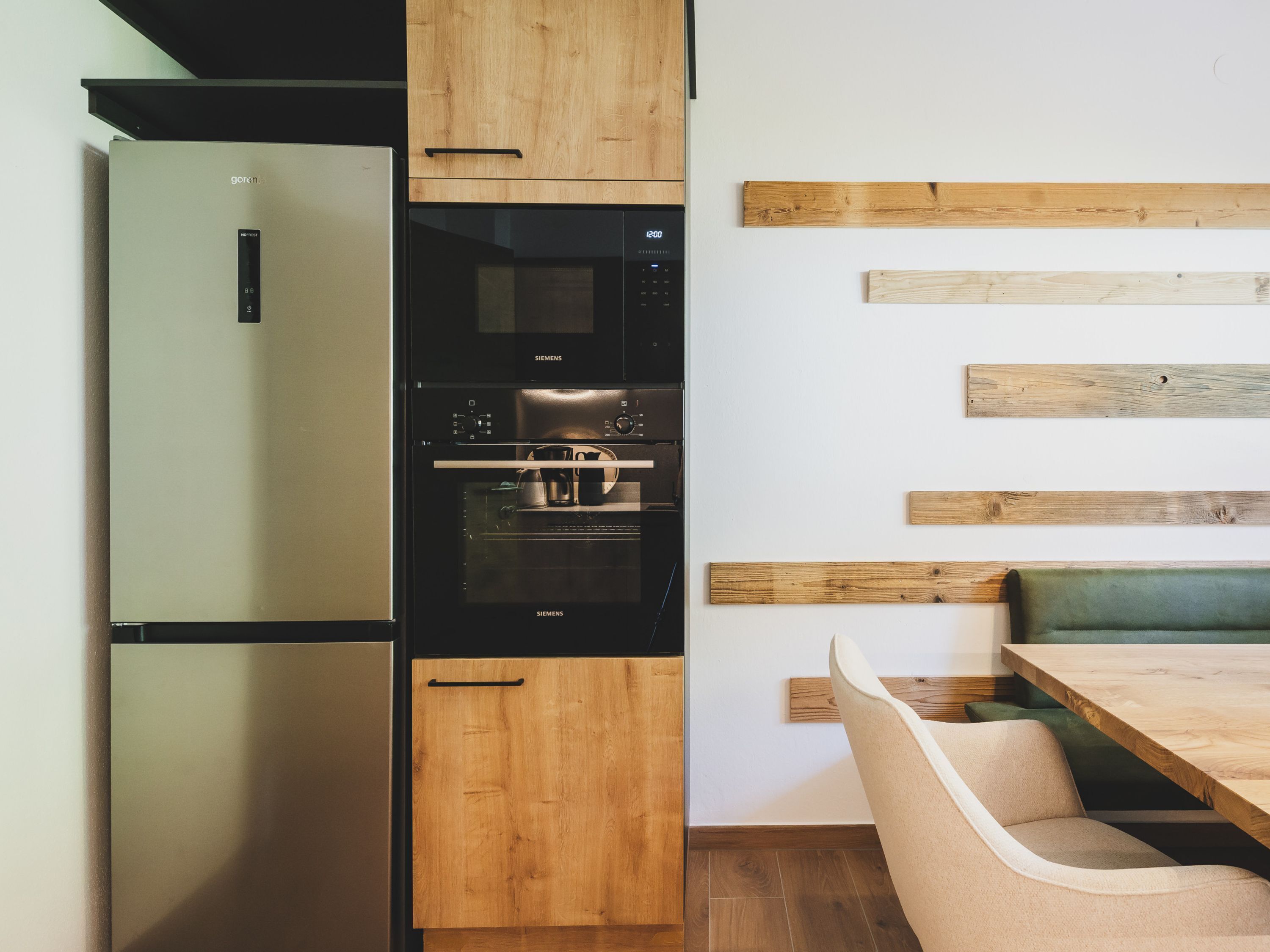 Une cuisine moderne équipée d’un réfrigérateur, d’un four et de meubles de rangement en bois.