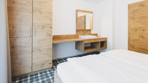 Ein Schlafzimmer mit einem hölzernen Kleiderschrank, einem Nachttisch, einem Spiegel und einem Bett.