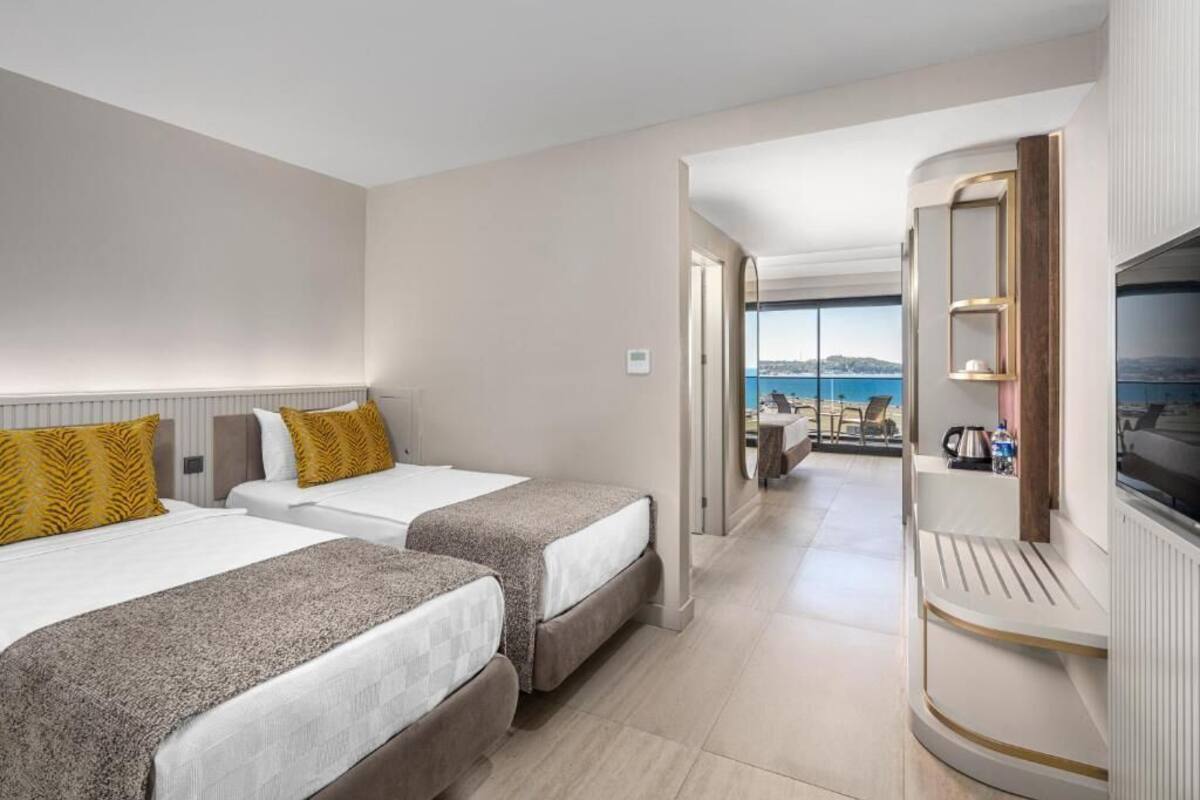 Een hotelkamer met twee bedden, een televisie en uitzicht op zee.
