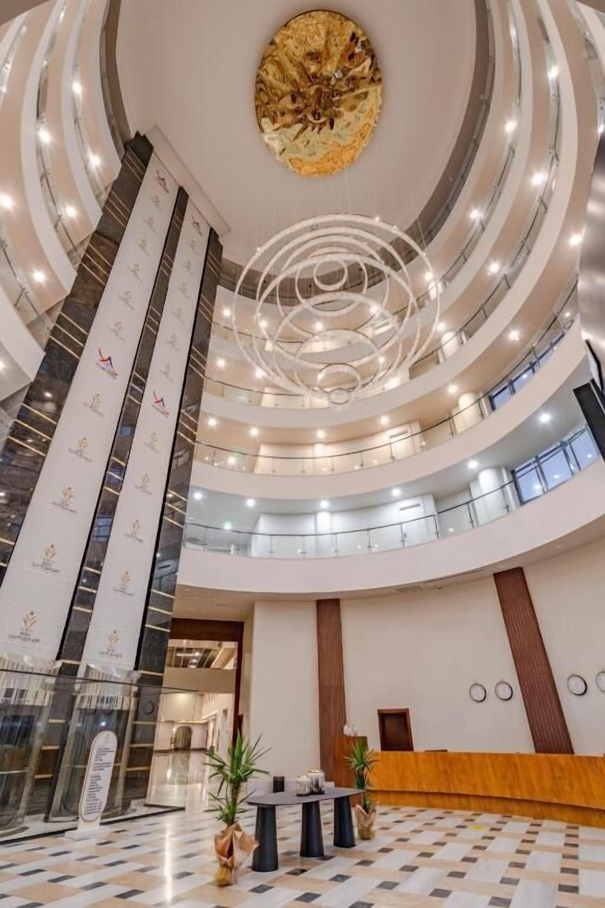 Um átrio com vários níveis, uma escadaria espiral central, uma receção e um teto decorativo.