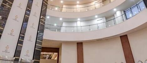 Um átrio com vários níveis, uma escadaria espiral central, uma receção e um teto decorativo.