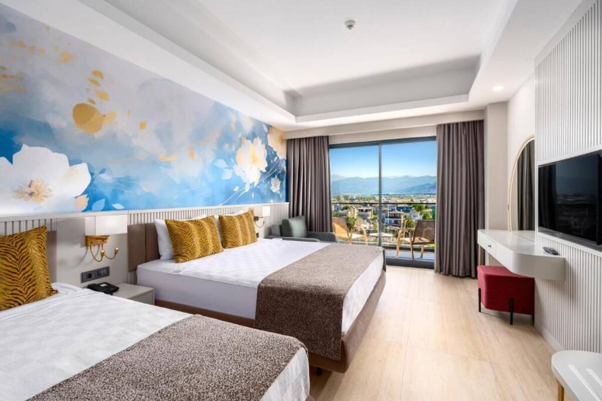 Een hotelkamer met twee bedden, een groot raam met uitzicht, een flatscreen televisie en een balkon.