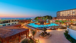 Ein Hotel mit einem großen Schwimmbad, mehreren Balkonen und Meerblick.