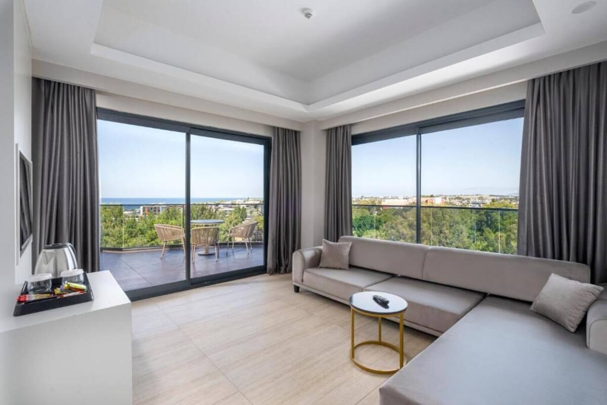 Een moderne woonkamer met een grote bank, een kleine ronde tafel en een balkon met uitzicht op de stad en zee.