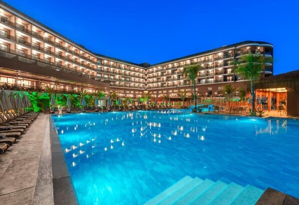 Ein Hotel mit einem großen Schwimmbad, mehreren Balkonen und Sitzbereichen im Freien.