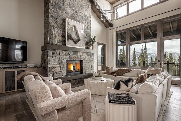 Un salón espacioso con chimenea de piedra, un televisor de pantalla plana grande y una zona de estar acogedora con sofá y sillones.