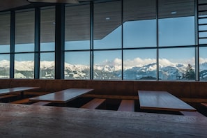 Un interior moderno con ventanas amplias que ofrecen vistas de montañas nevadas.