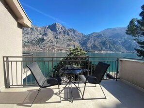 Un balcon avec une table et des chaises, donnant sur un lac et des montagnes.