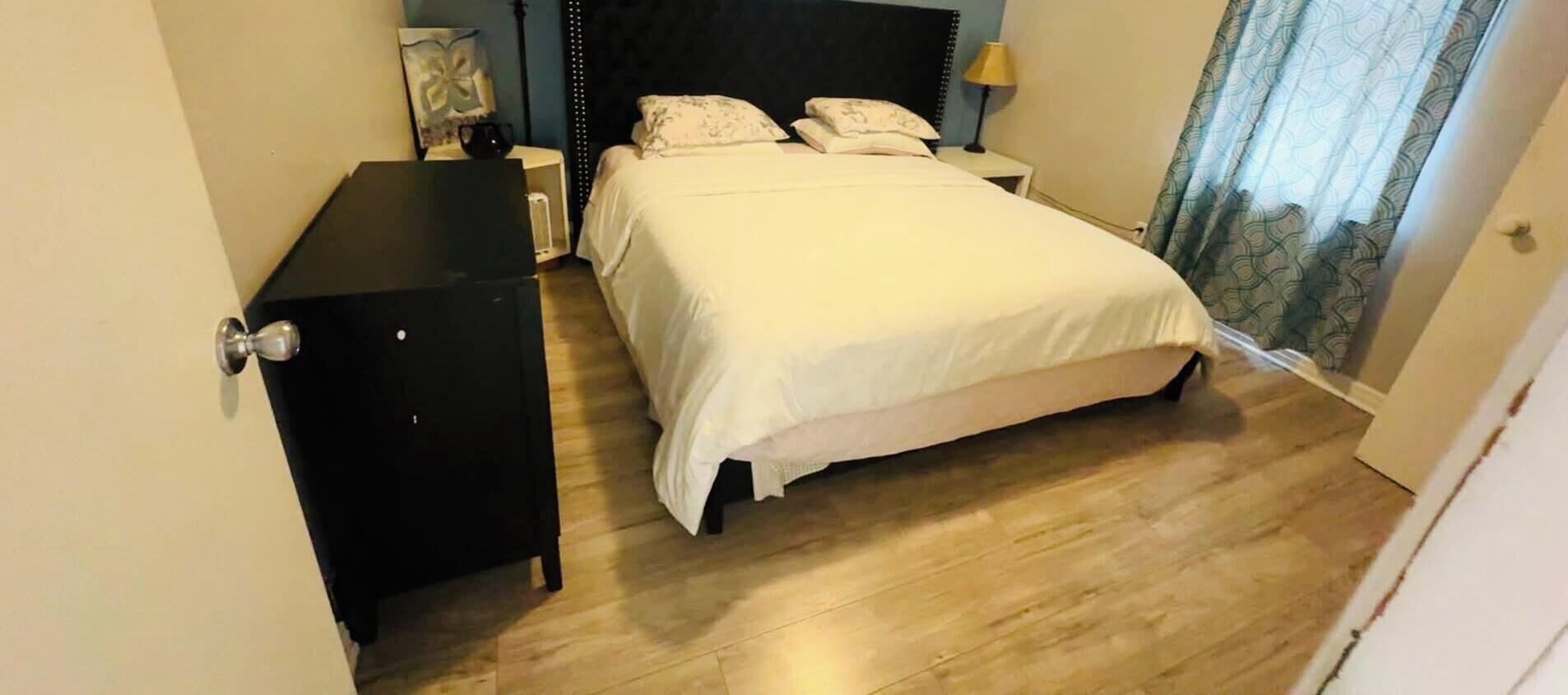A bedroom with a bed, bedside tables, and a wardrobe.
