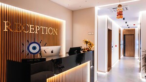 A reception area with a wooden slat wall, a reception desk, and an Apple laptop. - The Lord's Garden (Ksamil)