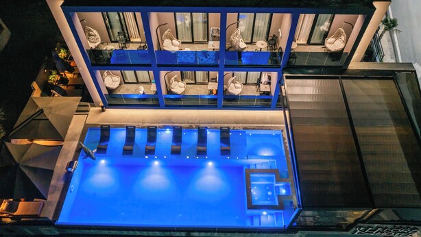 A modern hotel with a rooftop pool area, multiple seating areas, and a well-lit interior. - The Lord's Garden (Ksamil)