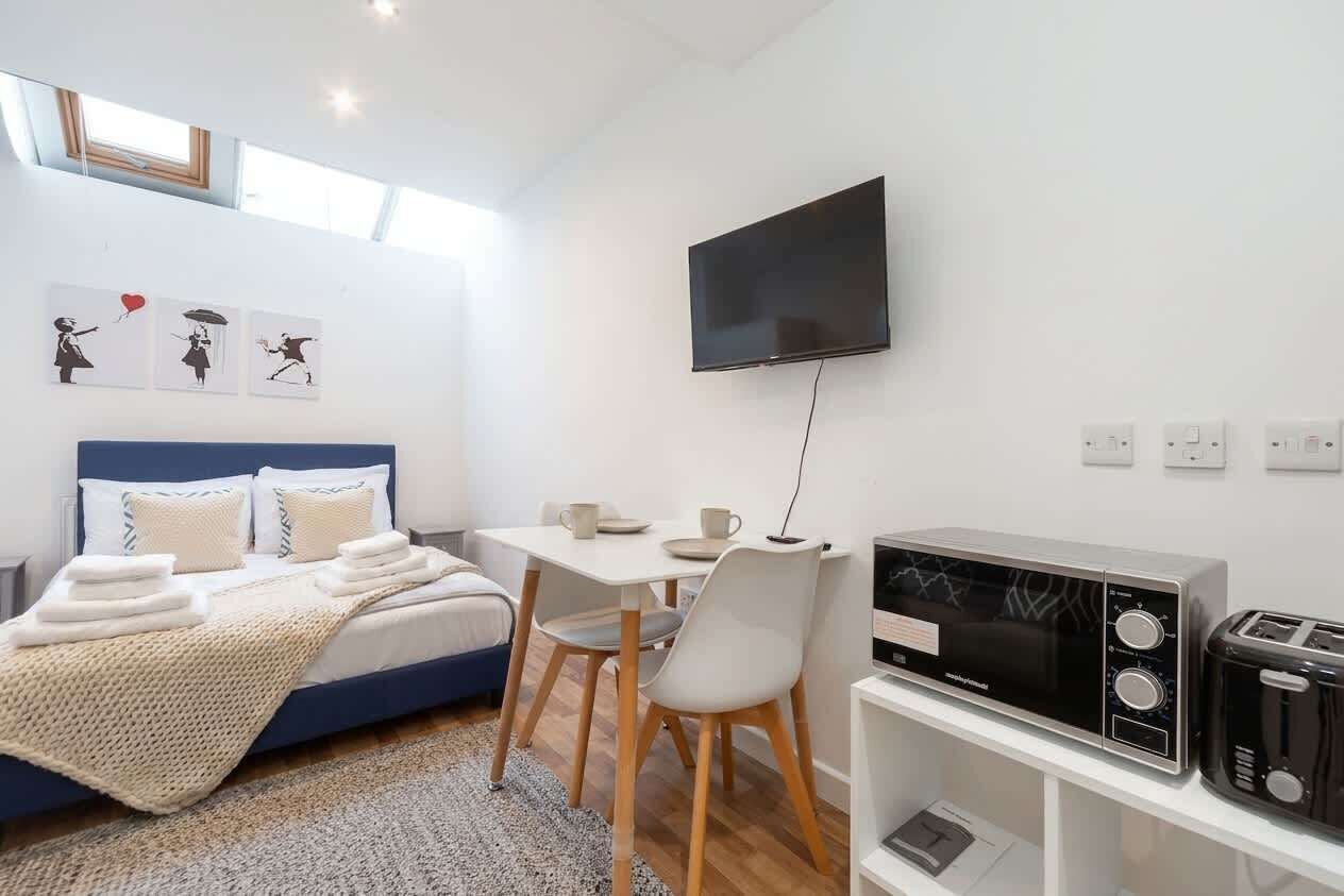 Ein Schlafzimmer mit Bett, Nachttisch und einem an der Wand montierten Fernseher.