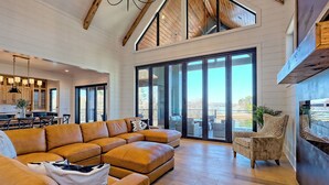 Un salón amplio con un sofá modular grande, piso de madera y un gran ventanal corredero que da a un balcón.
