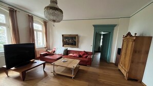 Una sala de estar con televisor, sofá, mesa de centro y candelabro.