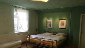 Un dormitorio con una cama, un sofá blanco y dos cuadros en la pared.