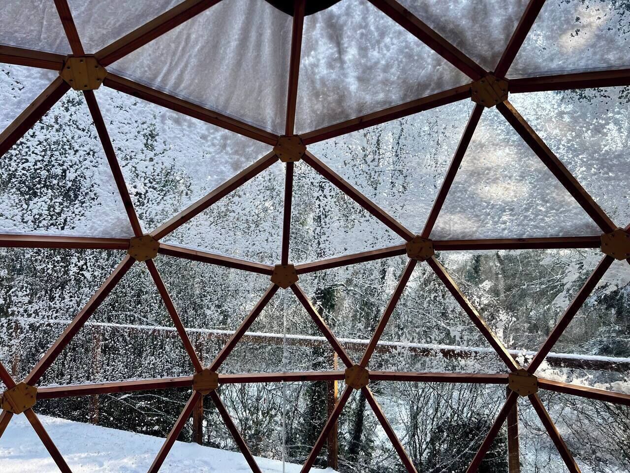 Geodeettinen kupurakenne, jonka läpinäkyvistä osista näkyy lumipeitteinen maisema.