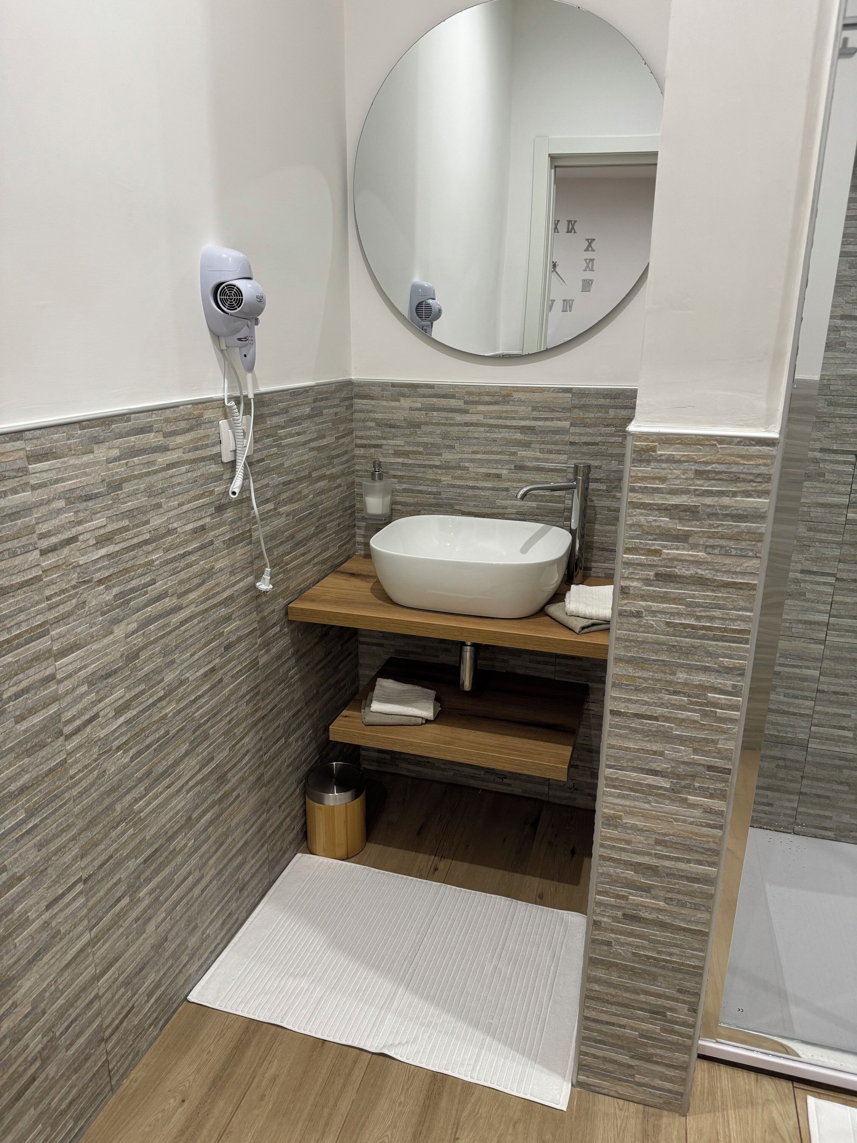 A bathroom with a white sink, a mirror, a hairdryer, and a towel rack.