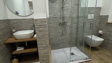 Ein modernes Badezimmer mit einer gläsernen Duschkabine, einem Holzbadezimmer-Möbel mit Waschbecken und einer weißen Toilette.