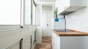 Una cocina moderna con armarios blancos, encimera de madera y salpicadero azulejado.