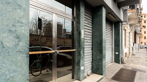 Una entrada de edificio con puerta de vidrio, una bicicleta y un toldo bajado.