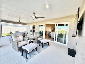 A spacious patio area with a ceiling fan, a dining table with chairs, and a seating area with sofas and a small table.