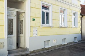 Un edificio amarillo con detalles blancos, una puerta con vidrio decorativo y un letrero con el número 3.
