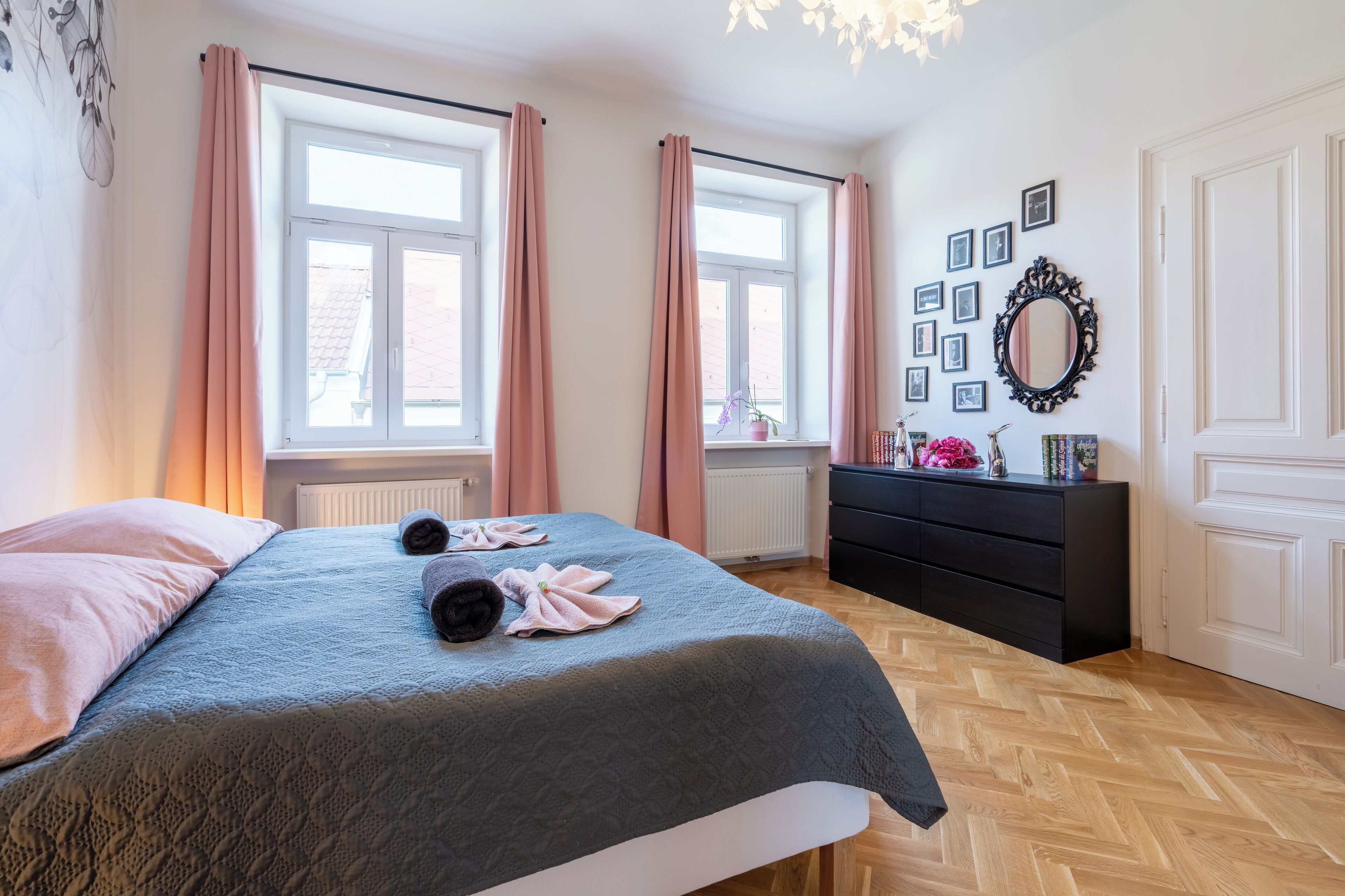 A bedroom with a bed, a dresser, a mirror, and a window with curtains.